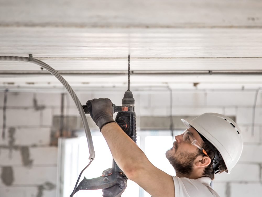 Handyman uses jackhammer, for installation, professional worker on the construction site. The concept of electrician and handyman. House and house reconstruction.